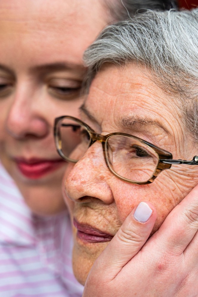 A caregiver resting close to an older woman